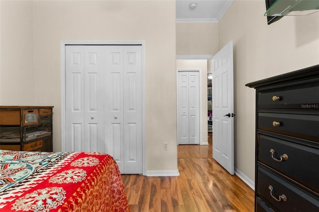 bedroom featuring a closet, baseboards, light wood-type flooring, and crown molding