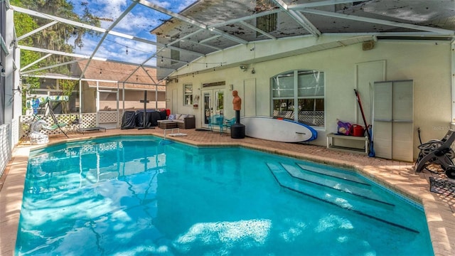 view of swimming pool featuring glass enclosure, a patio area, and french doors