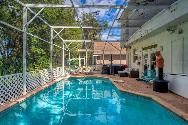 view of swimming pool featuring french doors, a patio, and a lanai