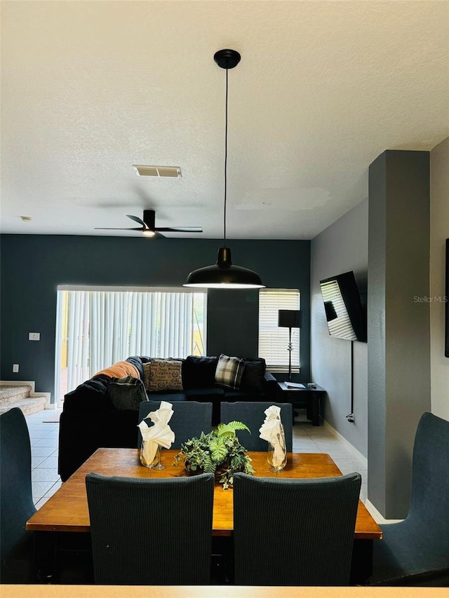 tiled dining room with a textured ceiling and ceiling fan