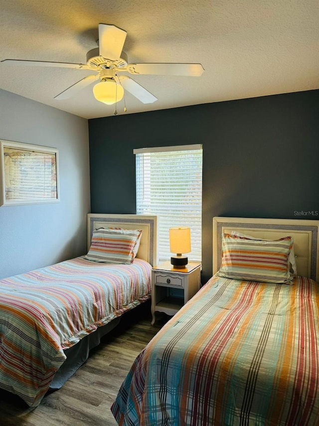 bedroom featuring hardwood / wood-style floors, multiple windows, a textured ceiling, and ceiling fan