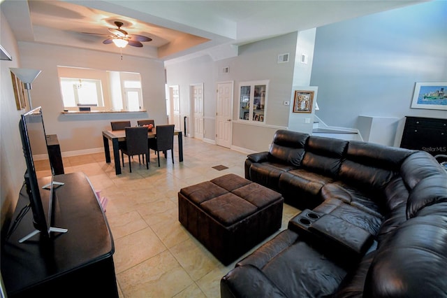 tiled living room featuring a raised ceiling and ceiling fan