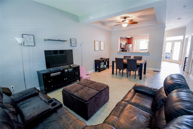 tiled living room featuring a raised ceiling and ceiling fan