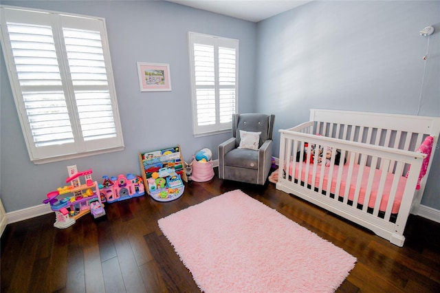 bedroom with a nursery area and dark wood-type flooring