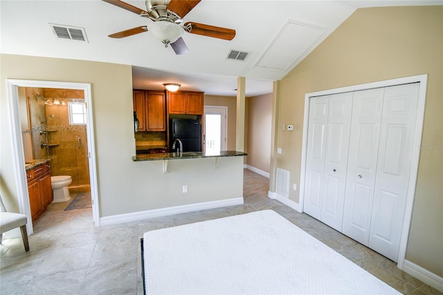 unfurnished bedroom featuring black fridge, a closet, connected bathroom, and multiple windows