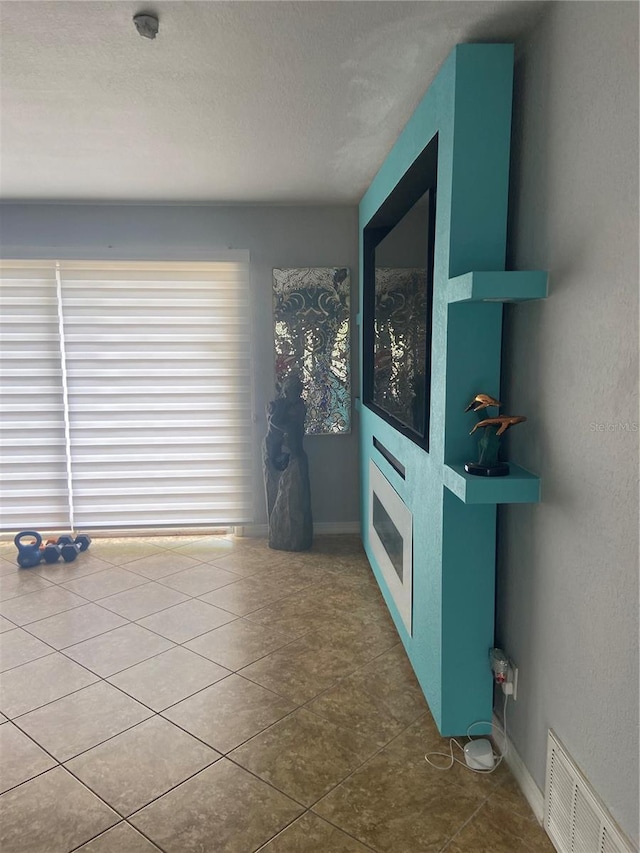 tiled spare room featuring visible vents, baseboards, and a textured ceiling