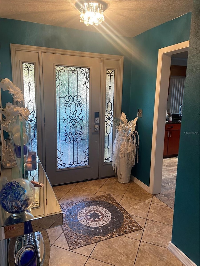 entryway featuring tile patterned flooring, a textured ceiling, and baseboards