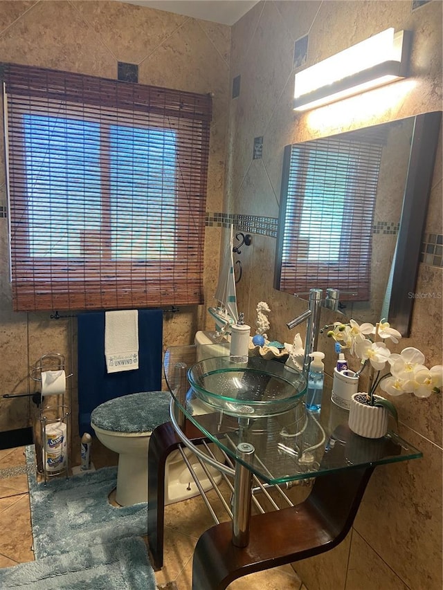half bathroom featuring tile walls, a sink, and toilet