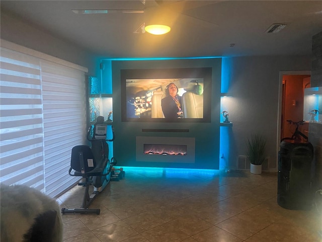 tiled living room with visible vents and a lit fireplace