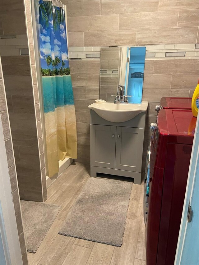 bathroom with separate washer and dryer, a shower stall, vanity, and wood finished floors