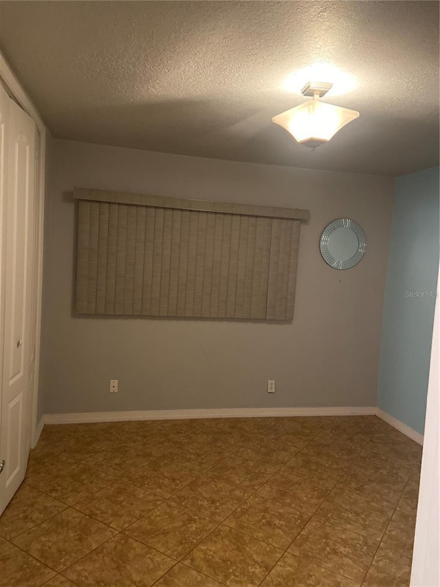 empty room with a textured ceiling and baseboards