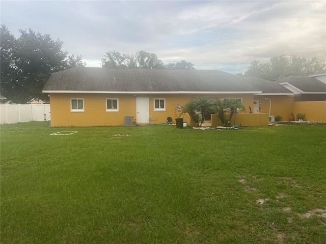 back of house featuring a yard, fence, and central AC unit