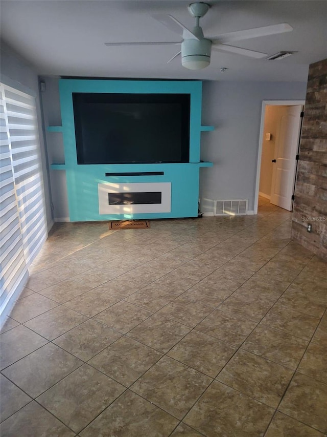 unfurnished living room with tile patterned floors, visible vents, baseboards, and ceiling fan