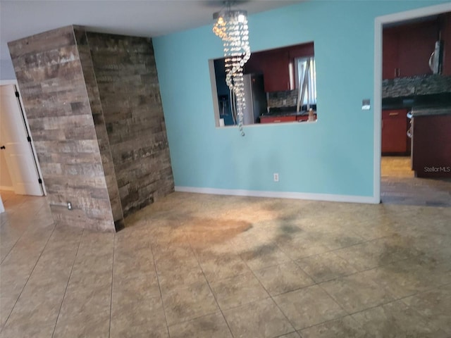 interior space featuring tile patterned flooring, baseboards, and a chandelier