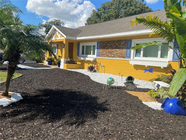 view of front of house featuring a shingled roof and stone siding