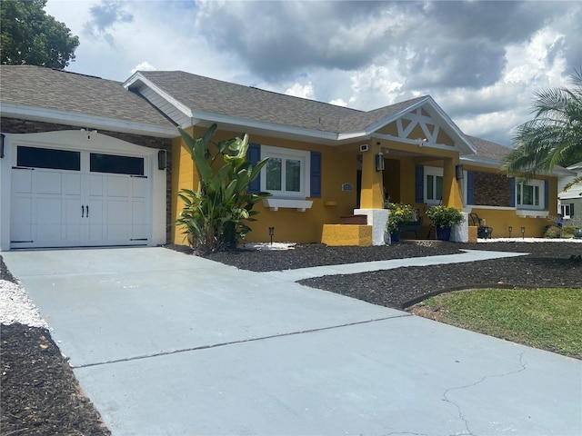 single story home with concrete driveway, roof with shingles, and an attached garage