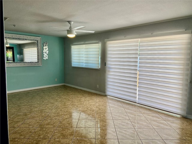 spare room with a textured ceiling, tile patterned floors, ceiling fan, and a wealth of natural light
