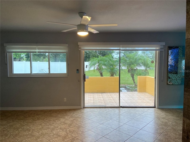empty room featuring baseboards, a ceiling fan, tile patterned flooring, and a wealth of natural light