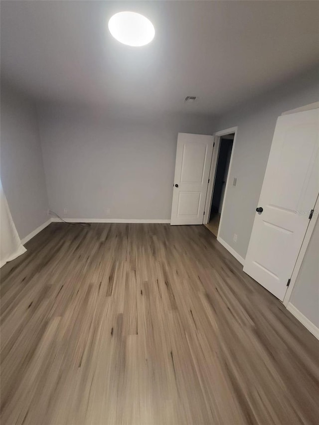 spare room featuring visible vents, baseboards, and wood finished floors