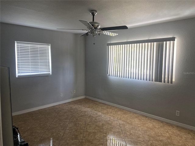 tiled spare room featuring baseboards and ceiling fan