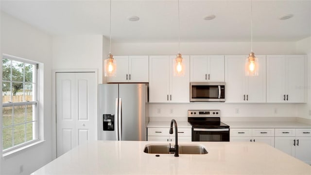 kitchen with appliances with stainless steel finishes, hanging light fixtures, and a wealth of natural light