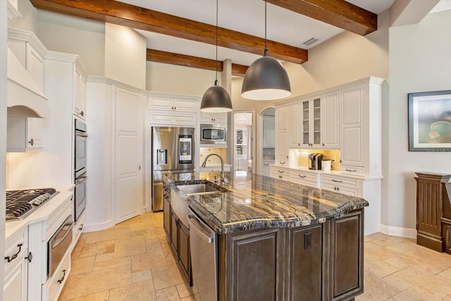 kitchen with hanging light fixtures, white cabinetry, beamed ceiling, dark brown cabinetry, and a center island with sink