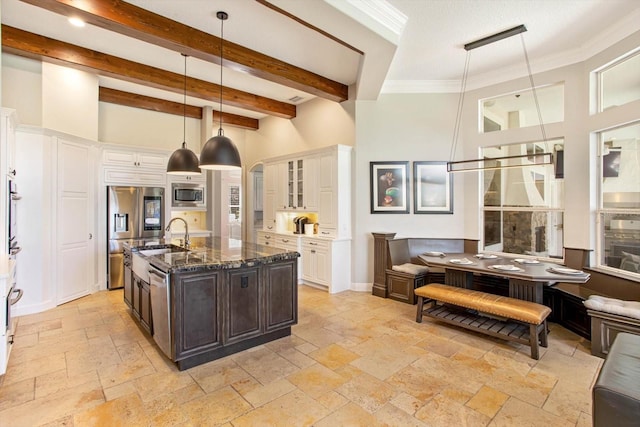 kitchen with hanging light fixtures, beam ceiling, dark brown cabinets, appliances with stainless steel finishes, and dark stone counters