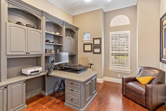 office featuring built in desk, ceiling fan, dark wood-type flooring, and crown molding