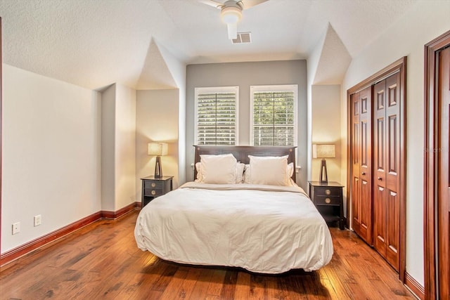 bedroom with a closet, vaulted ceiling, ceiling fan, and hardwood / wood-style floors