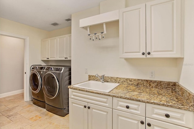 washroom with sink, washing machine and clothes dryer, and cabinets