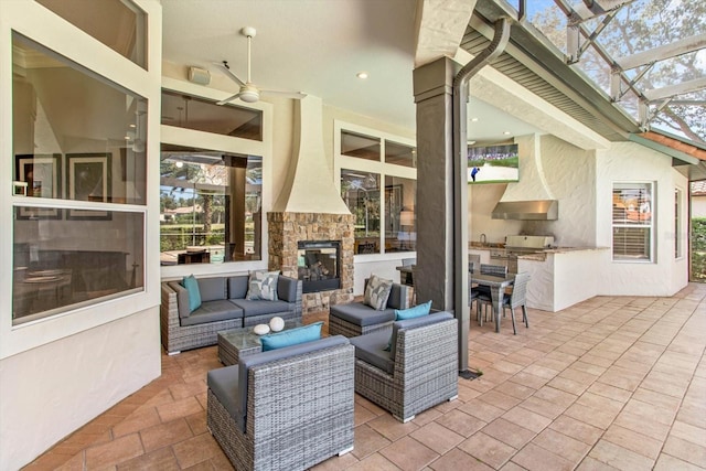 view of patio with ceiling fan, an outdoor hangout area, an outdoor kitchen, and glass enclosure