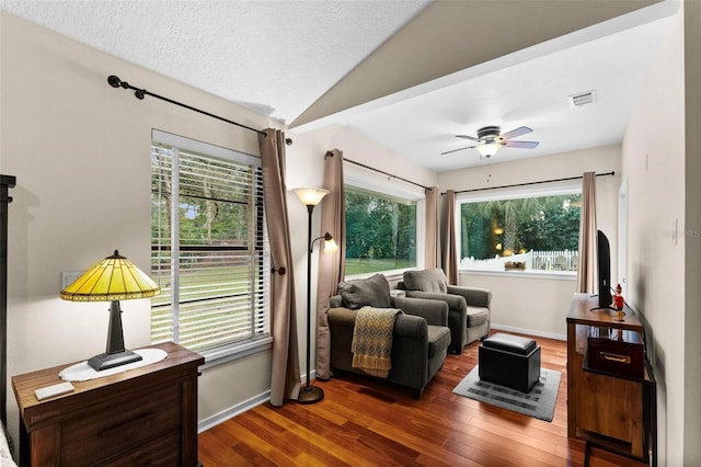 living room featuring dark wood-type flooring, ceiling fan, a textured ceiling, and lofted ceiling