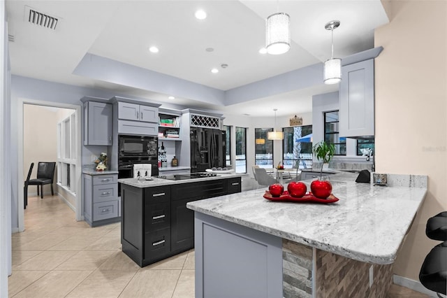 kitchen with light stone countertops, black appliances, kitchen peninsula, decorative light fixtures, and a breakfast bar