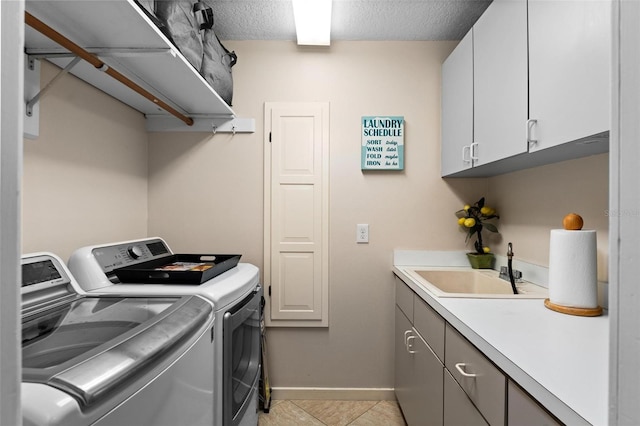 laundry area featuring washer and dryer, light tile patterned floors, sink, a textured ceiling, and cabinets