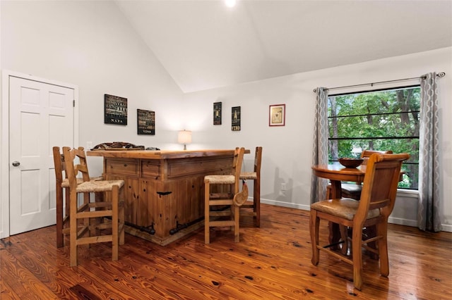 bar with dark wood-type flooring and high vaulted ceiling