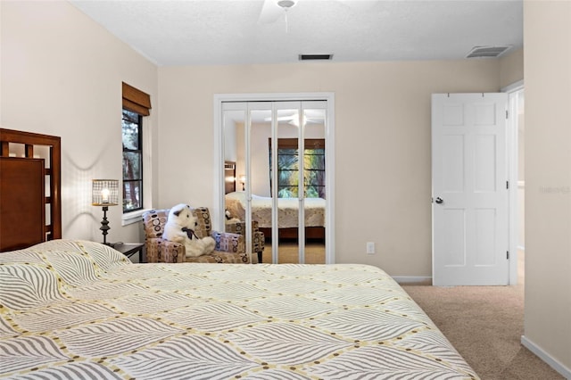 carpeted bedroom featuring a closet, ceiling fan, a textured ceiling, and multiple windows