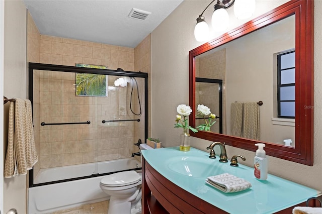 full bathroom featuring vanity, enclosed tub / shower combo, toilet, and a textured ceiling