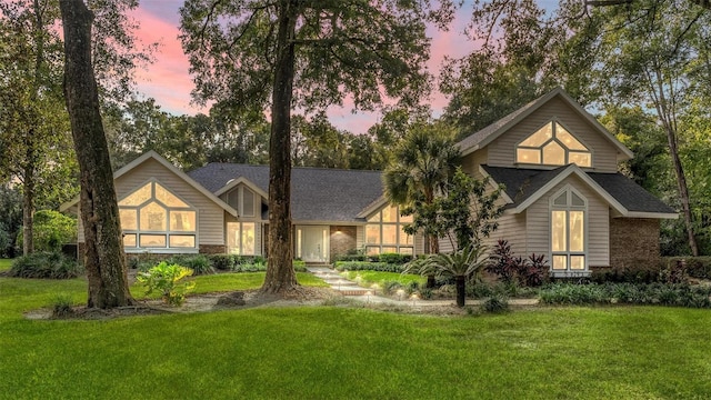 view of front of house featuring brick siding and a lawn