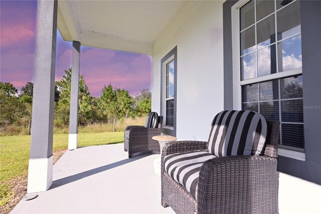 patio terrace at dusk featuring a lawn