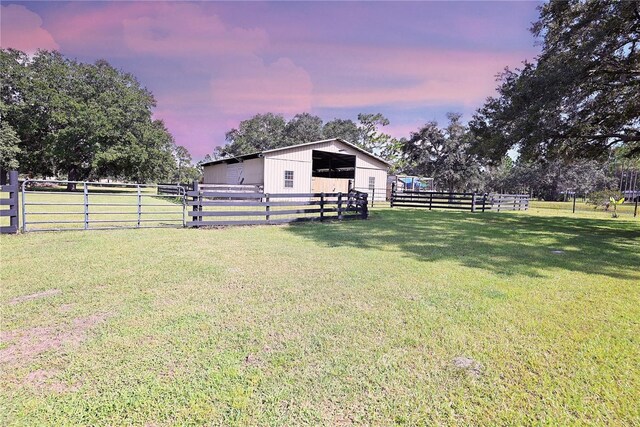 yard at dusk featuring an outbuilding and a rural view