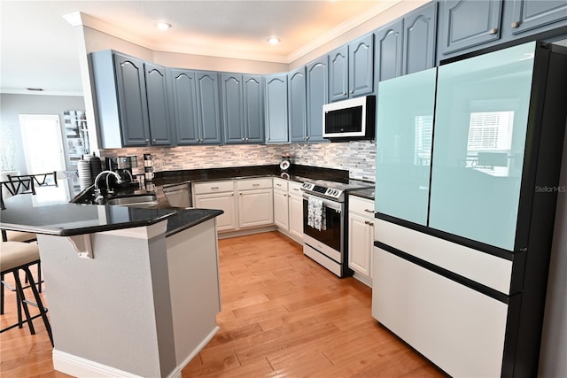 kitchen with sink, blue cabinets, white cabinetry, light hardwood / wood-style floors, and stainless steel appliances