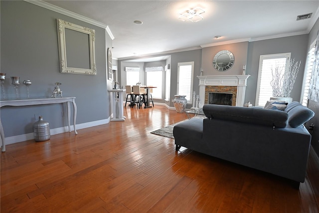 living room featuring ornamental molding, a stone fireplace, and hardwood / wood-style flooring