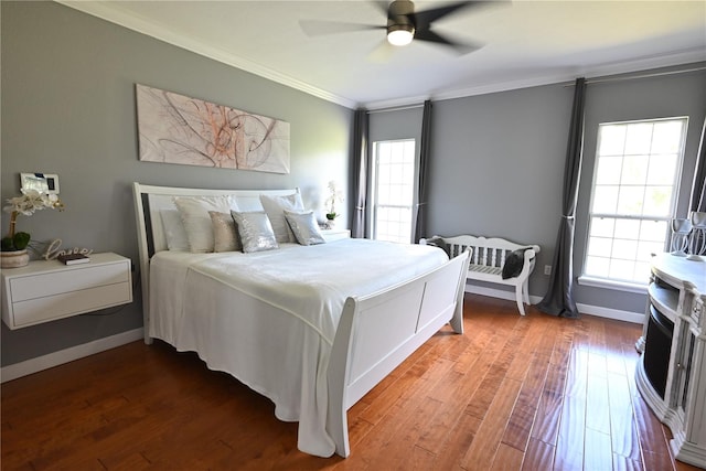 bedroom with multiple windows, wood-type flooring, crown molding, and ceiling fan