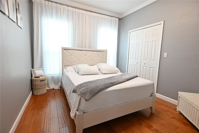 bedroom featuring hardwood / wood-style floors, crown molding, and a closet