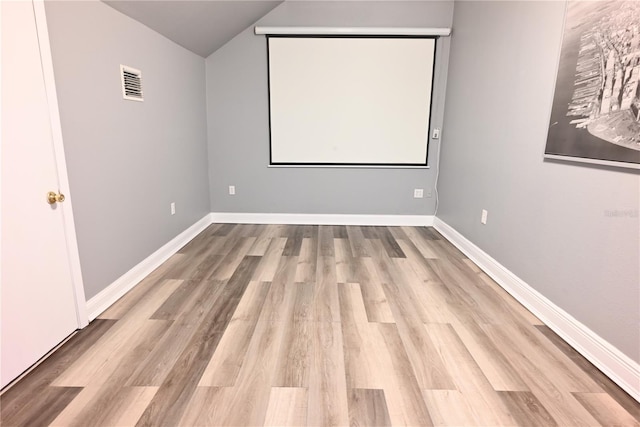 home theater room featuring light hardwood / wood-style floors and lofted ceiling