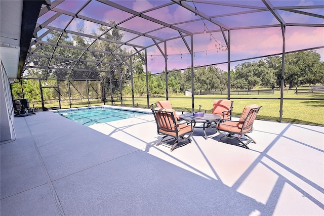 pool at dusk with a yard, a patio area, and a lanai