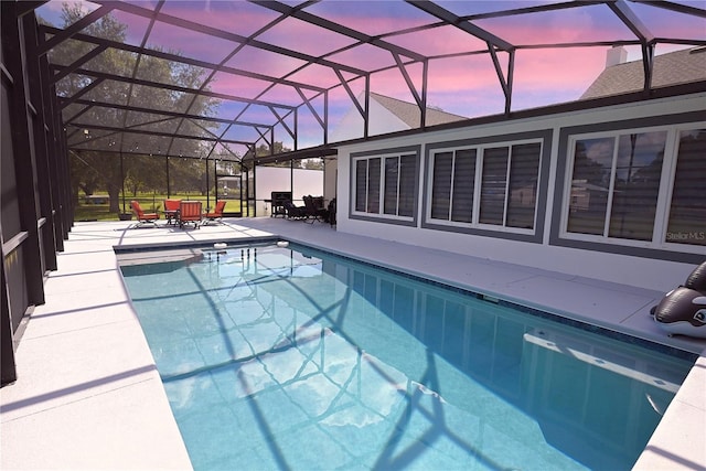 pool at dusk with a patio and a lanai