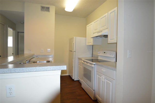 kitchen featuring a textured ceiling, dark wood-type flooring, white cabinetry, kitchen peninsula, and white appliances