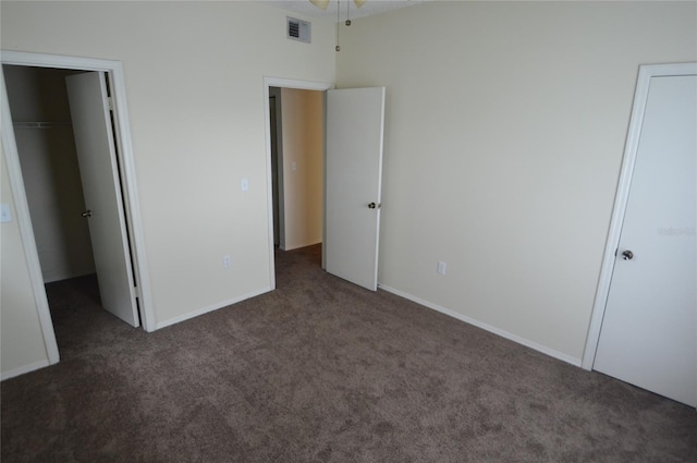 unfurnished bedroom with dark colored carpet and a closet