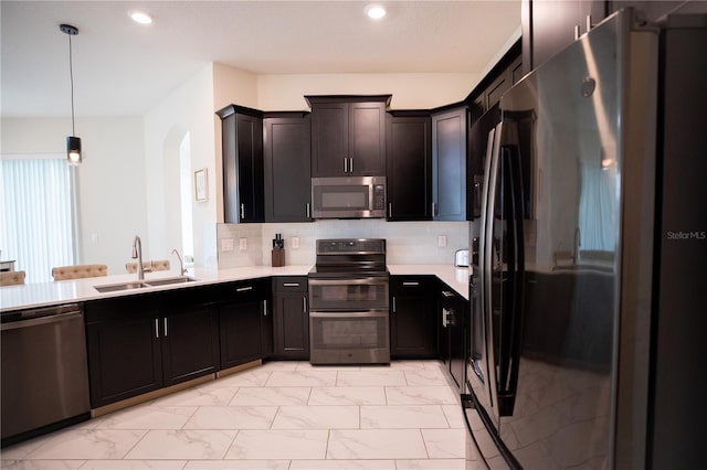 kitchen with appliances with stainless steel finishes, hanging light fixtures, backsplash, and sink